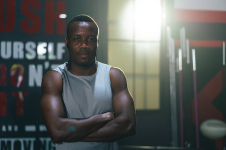 Portrait of African athlete cross arms looking at camera in fitness gymの写真素材