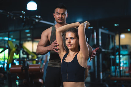 Young woman in sportswear with trainer in fitness club or gym.の写真素材