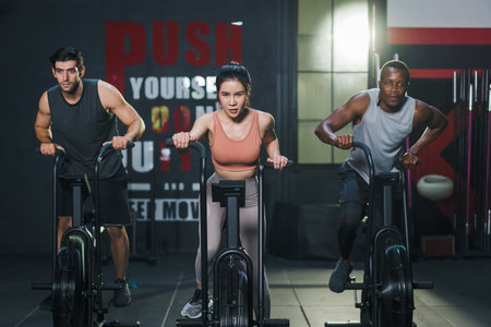 Multi ethnic group of sportsperson exercising on spinning bike cardio machine building muscle in fitness gymの写真素材