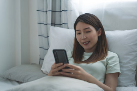 Asian woman taking selfie or making video call on smartphone to her friends or family while coronavirus pandemic and social distancingの写真素材