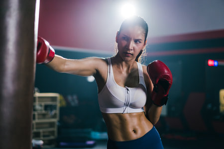 Young Asian is punching a sandbag training boxing or Muay Thai in the gym. Concept of Boxer and...