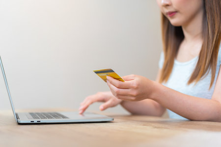 Asian woman holding a credit card typing on keyboard for online shopping or online banking