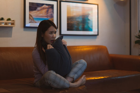 Asian woman watching horror movie scared at nightの写真素材