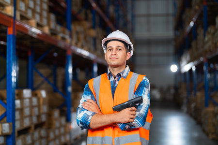 Portrait of a happy middle-aged Caucasian warehouse worker standing in large warehouse distribution...