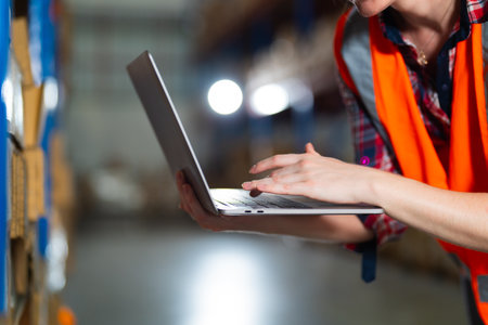 Warehouse worker working process checking the package using laptop in large warehouse distribution center. Caucasian female inspects storage and inventory.の写真素材