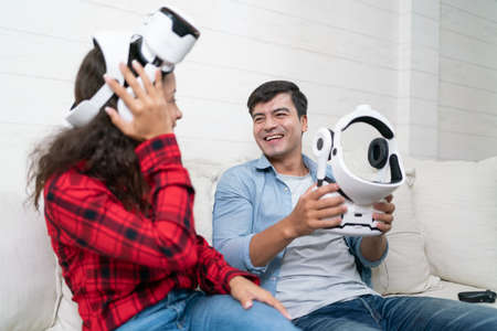 Happy young couple playing video games with virtual reality headset at home.の写真素材
