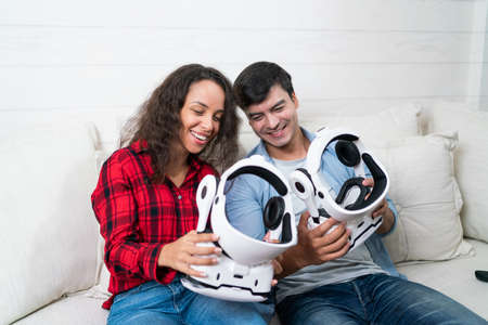 Happy young couple with virtual reality glasses sitting on the sofa at homeの写真素材