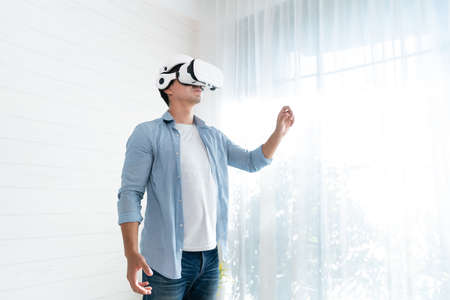 Asian man wearing virtual reality glasses at home. Virtual reality concept.の写真素材