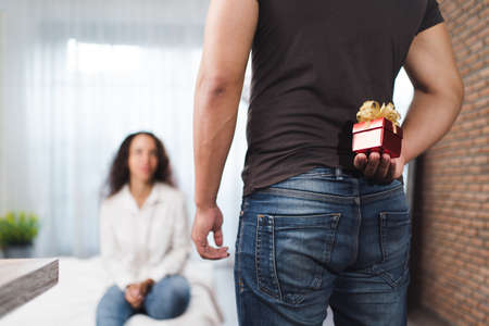 Man holding a gift box in front of a woman in the bedroomの写真素材
