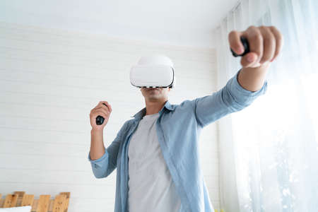 Asian man using virtual reality headset at home. VR technology concept.の写真素材