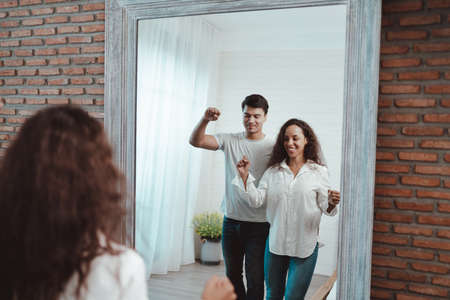 Young couple dancing in front of the mirror at home. The concept of a happy family.の写真素材