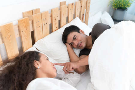 Couple in love lying on the bed at home and looking at each otherの写真素材