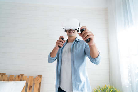 Asian man using virtual reality headset at home. VR technology concept.の写真素材