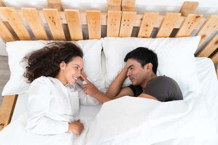 Couple lying in bed and looking at each other, top viewの写真素材