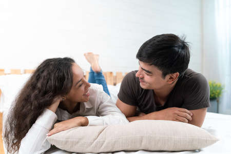 Happy young asian couple in love lying on bed at home.の写真素材