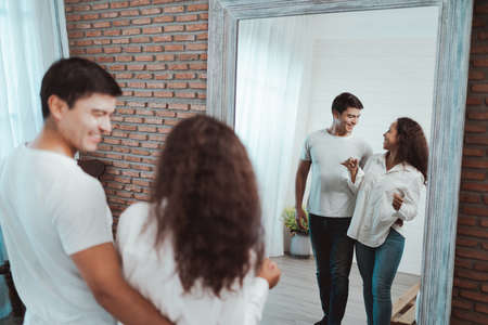 Group of young people talking in front of the mirror. The guy and the girl are looking at each other.の写真素材