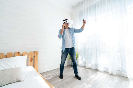 Young man wearing virtual reality goggles in the bedroom. VR technology concept.の写真素材