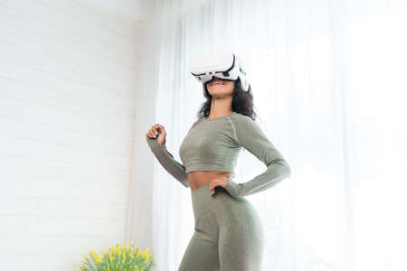 Young woman wearing virtual reality headset in the living room at home.の写真素材