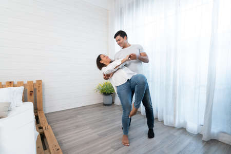 Young couple in love dancing at home. A man and a woman are dancing together.の写真素材