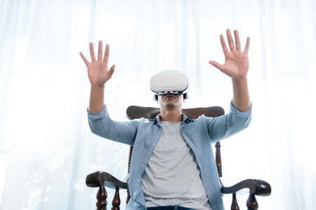 Cheerful man wearing virtual reality headset and gesturing at homeの写真素材
