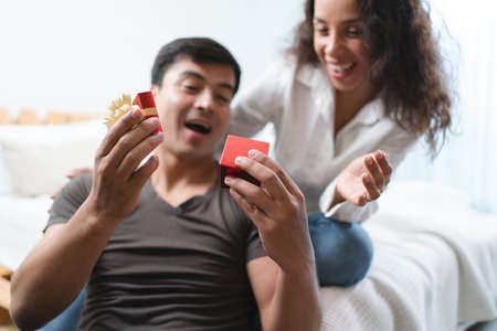 Happy young asian couple with gift box on bed at home.の写真素材