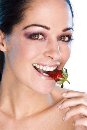 Beautiful young woman face. Close up. Portrait of young girl witn fresh strawberryの写真素材