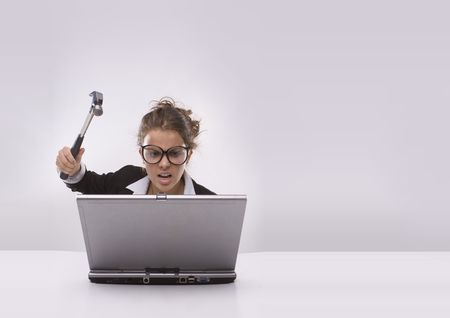  Angry brunette businesswoman with hammer and glasses against laptopの写真素材