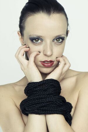 Young woman bondaged by rope in the studio の写真素材