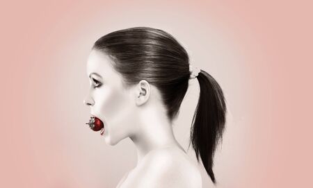 Beautiful woman biting strawberry artistic potrait side view の写真素材