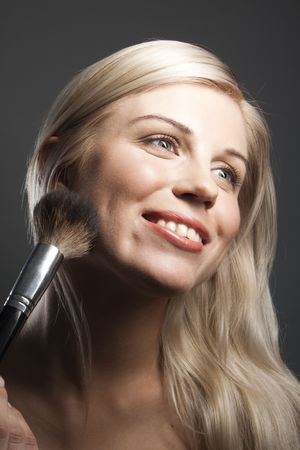 Portrait of smiling young woman with makeup brushの写真素材
