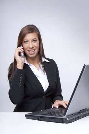 Beautiful happy Businesswoman on Phone working on her laptopの写真素材