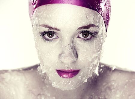 splashes and drops of water on  young female face wearing swimming hatの写真素材