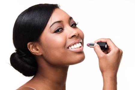 Portrait of a beautiful african black woman getting ready applying lipstickの写真素材