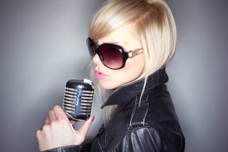 Rock star.Sexy Girl singing in retro mic on grey background ringflashの写真素材