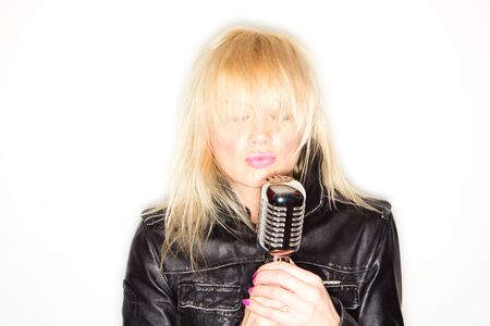 blonde woman holding a retro microphone wearing black jacket , singing rockstar