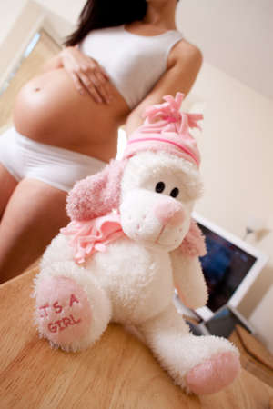 pregnant woman holding a small teddybear in her hand の写真素材