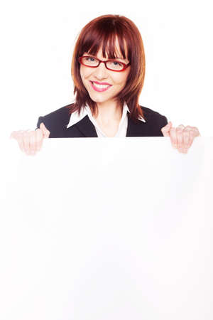 Friendly smiling young businesswoman wearing glasses holding a blank white signboardの写真素材
