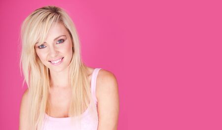 Portrait of young blonde woman on pink background copyspaceの写真素材