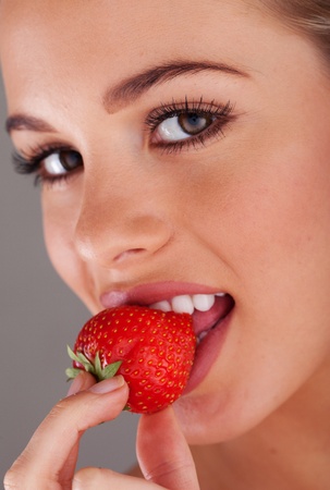 Happy young woman eating mellow strawberryの写真素材