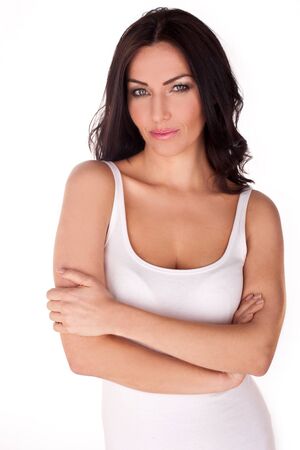 Brunette woman on a white background wearing a white tank top with arms crossed in front of herの写真素材