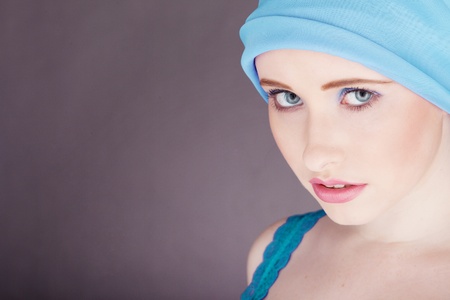 head shot of a woman wearing a blue tank top with blue fabric wrapped around head against a dark backgroundの写真素材