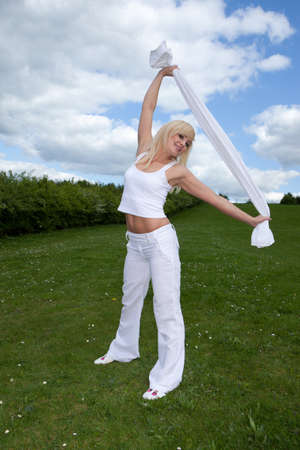 Athletic young blonde woman with a shapely body standing doing stretching exercises on a lush green lawnの写真素材