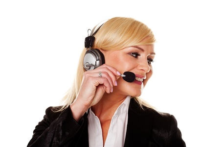 Smiling stylish professional woman using headphones and a mike as a receptionist, personal assistant or public relations officerの写真素材