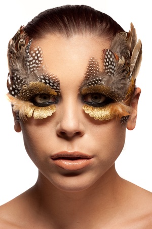 Beautiful woman wearing dramatic creative make-up of the feathers of wild birds framing and enhancing her eyesの写真素材