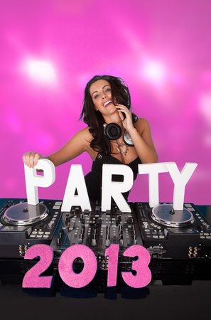 Pink PARTY 2013 with sexy vivacious female DJ laughing as she stands behind her music deck and turntables with copyspaceの写真素材