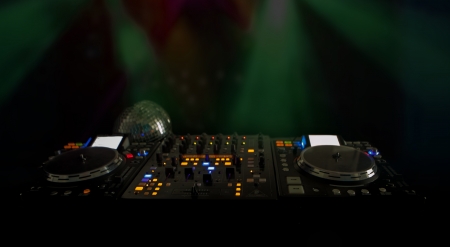Closeup of illuminated lights on DJs music deck and turntables at night with copyspace