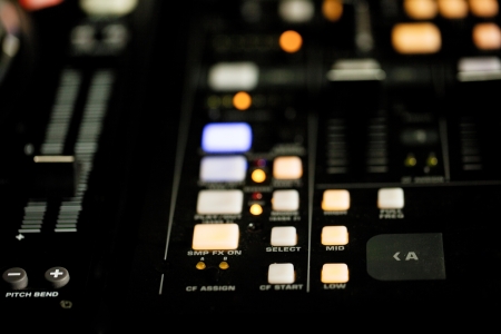 Closeup view of the illuminated lights on the deck of a DJ at night during a performance at a nightclub or discoの写真素材
