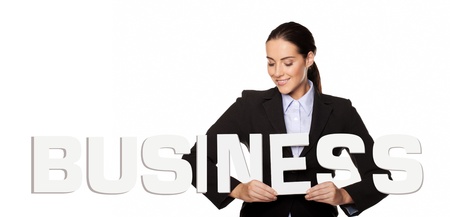 Smiling attractive businesswoman holding the word BUSINESS in white capital letters in her hands isolated on a white backgroundの写真素材