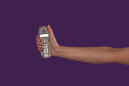 Female hand holding a remote control in the upright position with her arm extended over a purple studio backgroundの写真素材