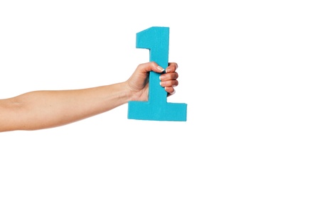Female hand holding up the number 1 against a white background conceptual of numbers, measurement, amount, quantity, accounting and mathematicsの写真素材